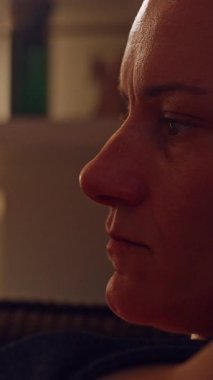 Dikey video. Ciddi Yetişkin Kadın Düşük Işık, Duygusal Odaklanma ve Dijital Yansıma Anında Akıllı Telefon Ekranına Bakıyor