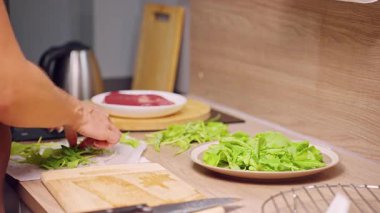 Mutfakta taze yeşil yaprakları düzenleyen kadın elleri, sağlıklı beslenme ve ev yemeği hazırlama.