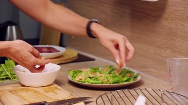 Mutfakta yeşil salata tabağına karides ekleyen kadın elleri dengeli beslenme ve sağlıklı yaşam tarzı.