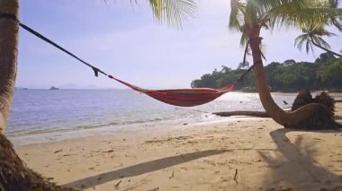 Çizgili hamak, kumsalın üzerinde, kumsalda asılı, güneşli deniz, tropikal dinlenme ve kıyı yaşam tarzı