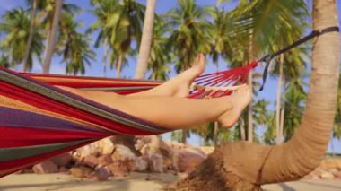 Çıplak kadın bacakları Sandy Tropikal Sahilinde Palmiye ağaçlarının arasında dinleniyor rahat tatil havası ve Yavaş Ada arasında dinleniyor.