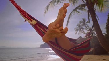 Kum ile kaplı çıplak kadın ayakları Tropikal sahilde dinleniyor Palmiye ağaçları ve yumuşak akşam ışığı ile