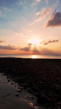 Dikey video. Günbatımında sakin okyanus ve dramatik bulutlar ile Rocky Tropikal Kıyı Şeridi 'nin Geniş Hava Görüntüsü, Altın Gün Işığı Huzurlu Seyahat Ortamı ve Doğal Özgürlük Yaratıcısı