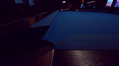 Geniş açılı mavi bilardo masası. Kadın karanlık kulüp iç mekanında çekim hazırlıyor. Odaklanma ve konsantrasyon gösteriyor.