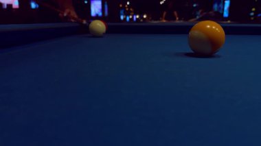 Mavi keçeli iki bilardo topunun yakın görüntüsü. Arka planda bir kadın çekim öncesi gerginlik yaratıyor.