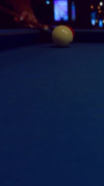 Dikey video. Mavi keçeli iki bilardo topunun yakın görüntüsü. Arka planda bir kadın çekim öncesi gerginlik yaratıyor.