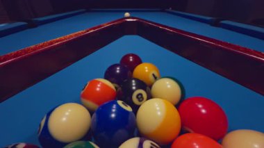 Mavi masadaki saçılmış bilardo topları dramatik bir şekilde düşük ışıkta çekilmeye hazır.