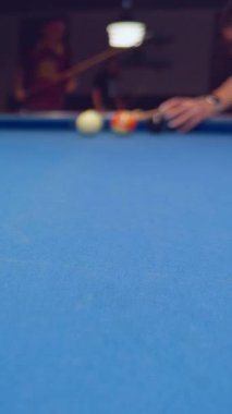 Dikey video. Dark bilardo kulübünün arka planında çekilen mavi bilardo topuna yakın çekim.