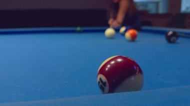 Kırmızı ve beyaz bilardo topunu yakın plan çekimleri için hazırlanan bir kadınla mavi masaya koyun.