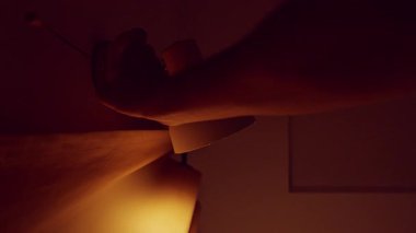 Karanlık odada lambanın yanması için zincir çekme düğmesi. Ilık ışık ev konforu ve akşam içinin atmosferini oluşturur.