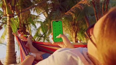 Tropikal Palm Garden 'da Yeşil Ekran ile Hamak Smartphone Besleyen Kadın, Sosyal Medya Taraması ve Mobil Teknoloji Eğlencesi İlk Kişi Görünümü