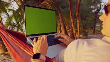 Yeşil Ekran ile Laptop 'ta Çalışan Kadın Tropikal Plajda Hamak' ta Dinlerken Uzaktan Çalışma Yaşam Tarzı ve Açık Hava Dijital Üretimi Gösteren İlk Kişi