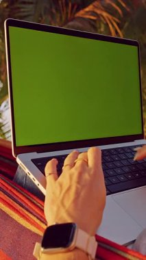 Dikey video. Yeşil Ekran ile Laptop 'ta Çalışan Kadın Tropikal Plajda Hamak' ta Dinlerken Uzaktan Çalışma Yaşam Tarzı ve Açık Hava Dijital Üretimi Gösteren İlk Kişi