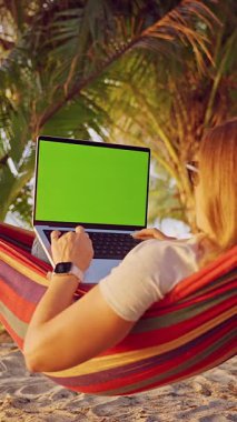 Dikey video. Hamakta Yatan Kadın, Kumsalda Yeşil Ekran, Geniş Açı Görünüm, Dijital Göçebe Çalışmaları ve Seyahat Yaşam Tarzını Gösteriyor