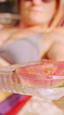 Dikey video. Hamaktan Taze Guava Dilimli Kadın Konteynırı Davet Etme Tropikal Yemek ve Eğlence Atmosferi
