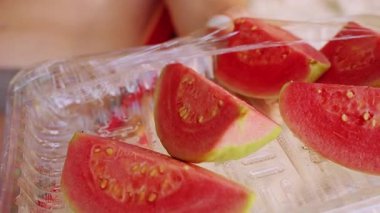 Plastik kabın içinde taze dilimlenmiş Guava 'ya yaklaş. Tropikal meyve dokusunu ve sağlıklı atıştırmalık detaylarını göster.