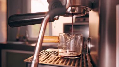 Espresso makinesi operasyonu sırasında aşırı basınçtan dolayı iskele filtresinden su sızıyor. Sıcak güneş ışığıyla görüş açısını kapayarak hazırlanırken hata ve teknik hatayı açığa çıkarıyor.