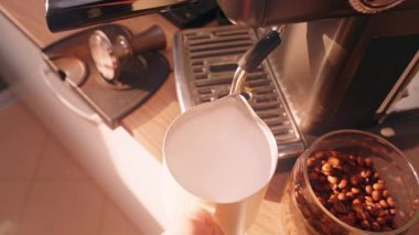 Espresso hazırlama sırasında evde sıcak ışık ve yavaş çekim ile köpük dokusunu pürüzsüz tutmak için buharda dönen sütçü.