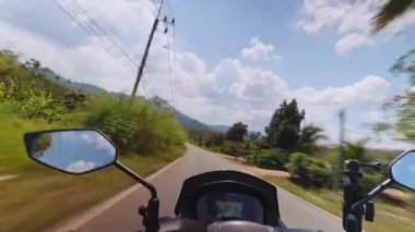 Dar tropikal yolda, palmiye ağaçlarının elektrik hatları ve mavi gökyüzünün güçlü hareket bulanıklığı ve hız, seyahat ve yol özgürlüğü hissi yarattığı Scooter 'ın ilk görüntüsü.