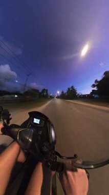 Dikey video. Sokak lambaları altında boş yolda ilk gece scooter sürüşü Özgürlük ve Hız Bulanıklığı