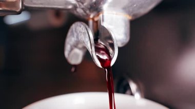 Koyu kırmızımsı Espresso akıntısının Portafilter 'dan Kupa' ya akışına yakın çekim aşaması ve kahve hazırlama sırasında zengin sıvı dokuyu gösteren
