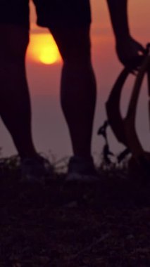 Dikey video. Çimenden Sırt Çantası Toplayan Kadın Silueti ve Parlak Güneş ve Ada Ufku Seyahat Macerası ve Özgürlük Gösteren Okyanus Günbatımında Cliff Edge 'den Ayrılmak
