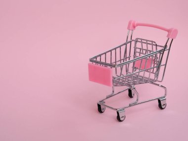 Pembe arka planda küçük boş market arabası