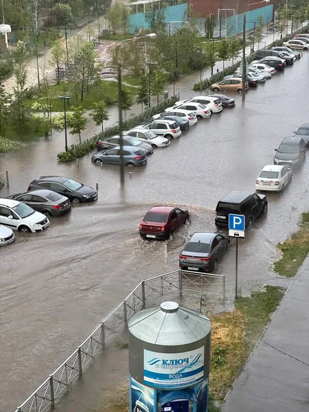 01 juin 2020 - Rue Absalyamov, Kazan, Russie : inondation après pluie dans la rue d'une grande ville, une voiture traverse une flaque d'eau profonde. Inscription en russe - clé de la santé. Eau — Photo