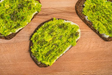 Tahta üzerinde avokado tostu. Ekmek, avokado püresi ve baharatlar. Yemek ve sağlıklı yiyecekler..