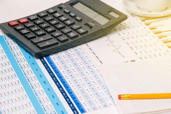 Analizci ofis işi. Hesap makinesi, not defteri ve finansal belgelerle çalışma masası. Şirket muhasebesi. Uzak çalışma ve eğitim