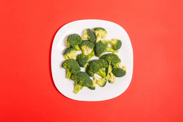 Broccoli Kvistar Vit Platta Röd Bakgrund Mogna Grönsaker Kål Näring — Stockfoto