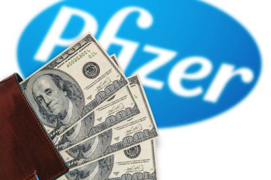 Dolarlı cüzdan ve bulanık Pfizer logosu. Pfizer aşı Coronavirus 'a karşı maliyet konsepti, covid-19: NEW YORK, ABD, 30 Kasım 2020.