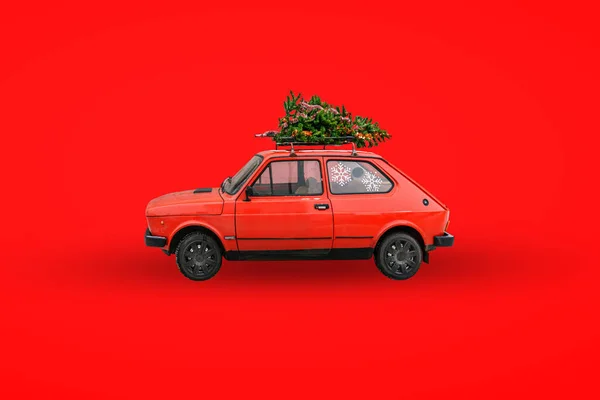 Kırmızı retro araba. Arabanın çatısında Noel ağacı var. Mal teslimatı, yeni yıl gezileri ve turlar. Noel arkaplanı