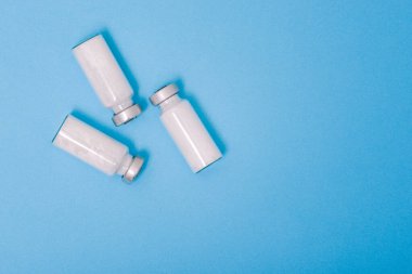 Coronavirus aşısı. Mavi arka planda morina ilacı olan cam şişe. Virüs koruması. Aşı geliştirme ve aşılama. Sağlık ve İlaç Hizmetleri