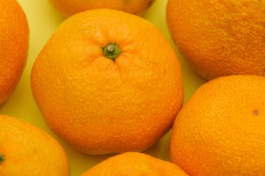 Mandalina kapanıyor. Sarı arka planda olgun mandalinalar. Vitaminli sağlıklı yiyecekler. Dokunulmazlık için meyve.