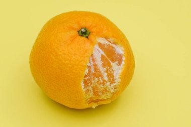 Olgun mandalina yakın çekim. Sarı arka planda mandalinayı ısırmış. Bağışıklık ve sağlık için turunçgil meyvesi.