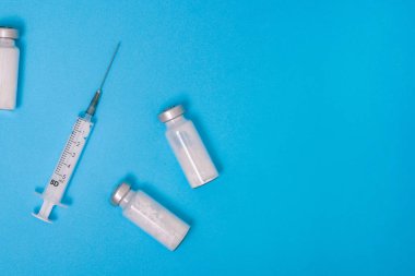 Eczacılık cam ampulü. Fotokopi alanı olan mavi bir arka planda tıbbi şırınga. İğne için beyaz toz. Hastalıkların, enfeksiyonların ve koronavirüsün tedavisi için antibiyotik. Covid-19 aşısı.