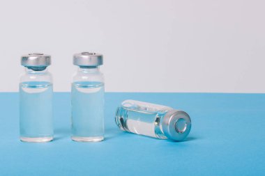 Covid-19 için yeni aşı. Mavi arka planda sıvı bulunan cam şişe. Covid-19, 2019-NCov salgını. Coronavirus aşısı