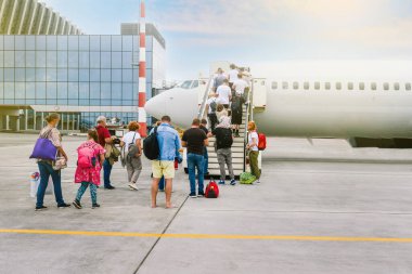 Uçağa binen yolcular. Bagajlı insanlar merdivenlerden çıkıp uçak kabinine giderler. Yolcu uçağı. Seyahat ve turizm konsepti. Modern uluslararası havaalanı.