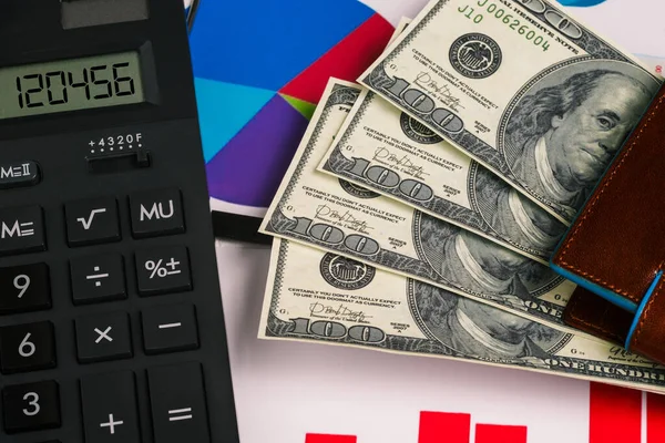 Calculator, growth charts and dollar bills in the wallet. Company cash, investments and company profits. The concept of success and making money.