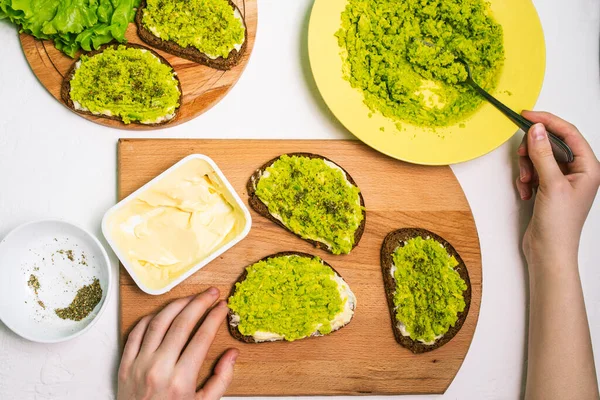 Appetizing appetizer with avocado. The process of making sandwiches for breakfast, lunch and dinner. Healthy food concept. Brown cereal croutons with salted and peppered avocados. Top view, flat lay — 图库照片