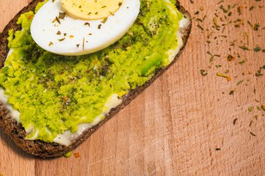 Sandwich with egg and mashed avocado. Close-up of toast on a wooden board. Healthy food for breakfast, lunch or dinner. Close-up, copy space