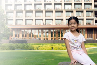 Asyalı kız gülümseyerek oturuyor.