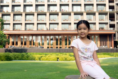 Asyalı kız gülümseyerek oturuyor.