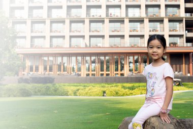 Asyalı kız gülümseyerek oturuyor.