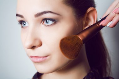 Güzellik makyaj fırçaları ile genç kız. Doğal makyaj bleu gözlü esmer kadın için. Güzel yüzüm. Makyaj. Mükemmel cilt. Makyaj uygulamak 