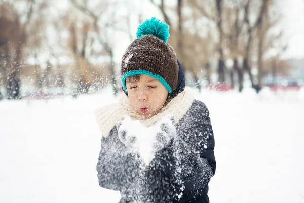 Boy blowing snow in the cold winter snow-covered park — Stock Photo, Image