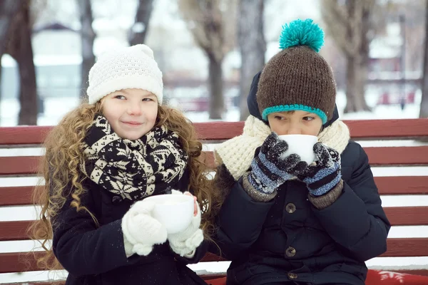 Boy with girl drink coffee together in the winter on a bench in — Stock Photo, Image
