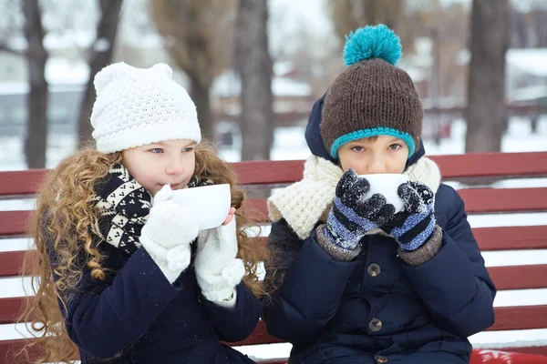 Boy with girl drink coffee together in the winter on a bench in — Stock Photo, Image