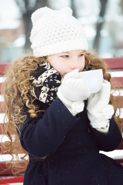 Little girl heated hot coffee frosty winter in snow-covered park — Stock Photo, Image